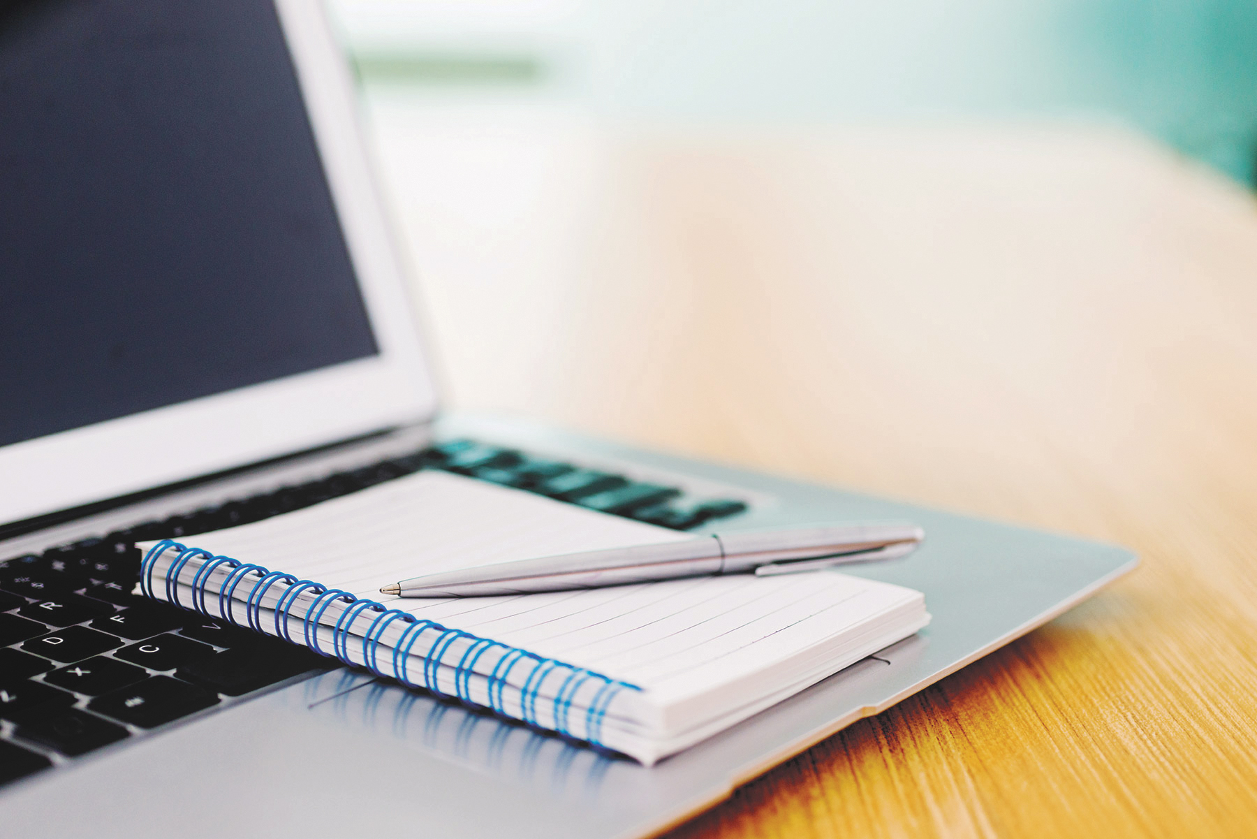 Note pad and pen sitting on laptop