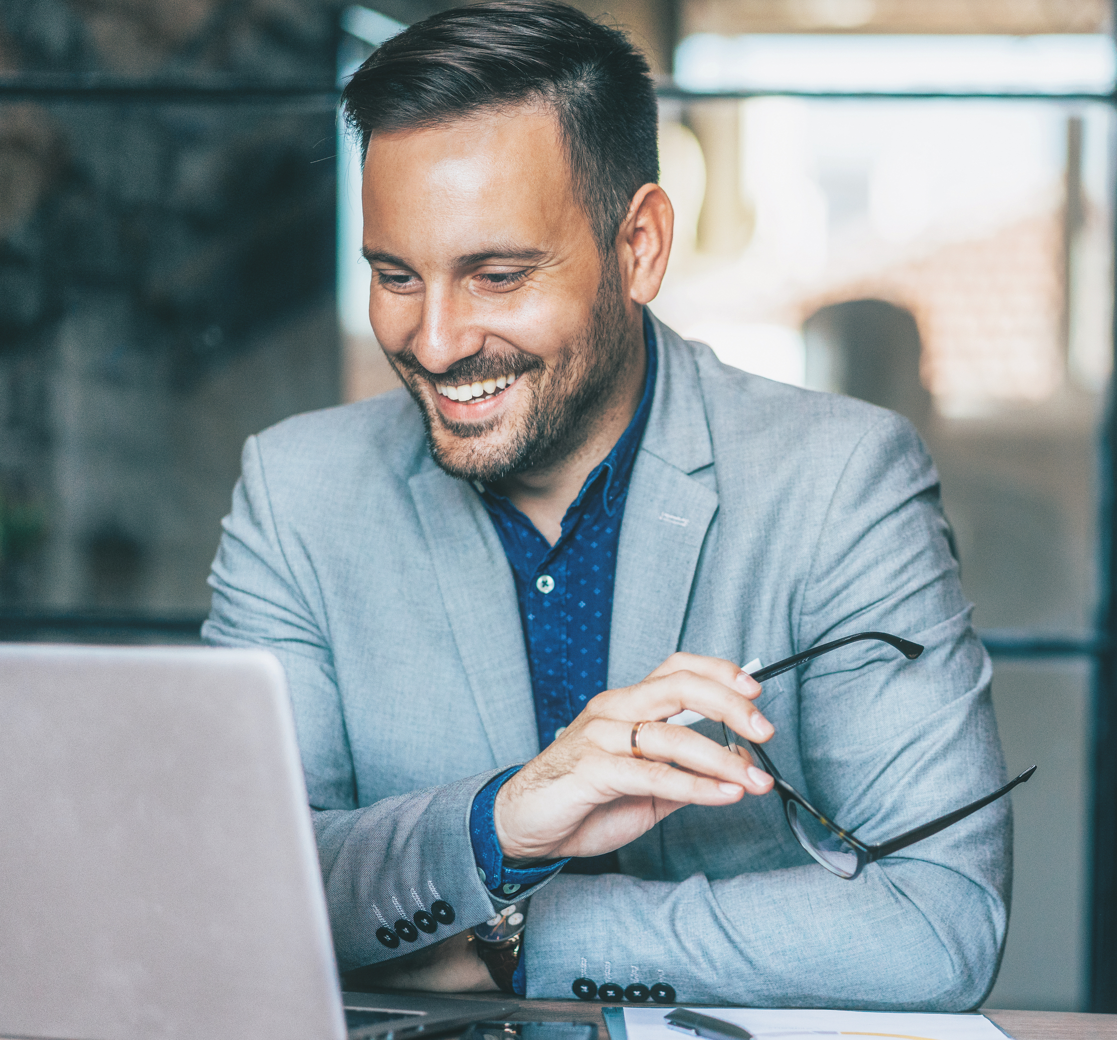 A man smiling and looking at his laptop.