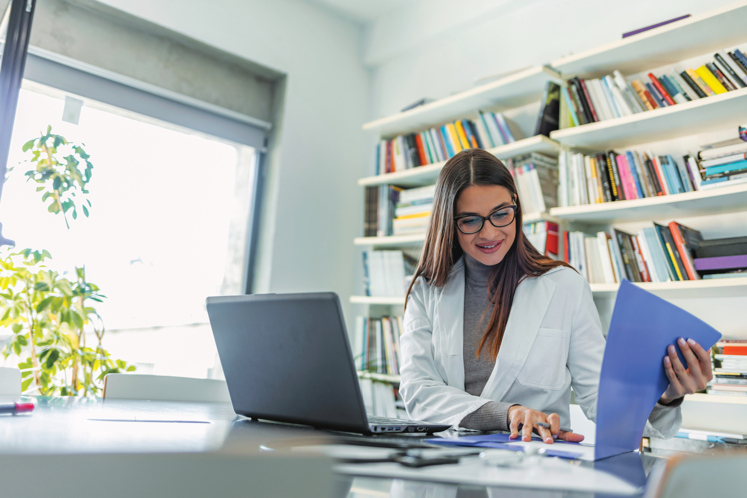 A medical professional reviews her notes in her office.