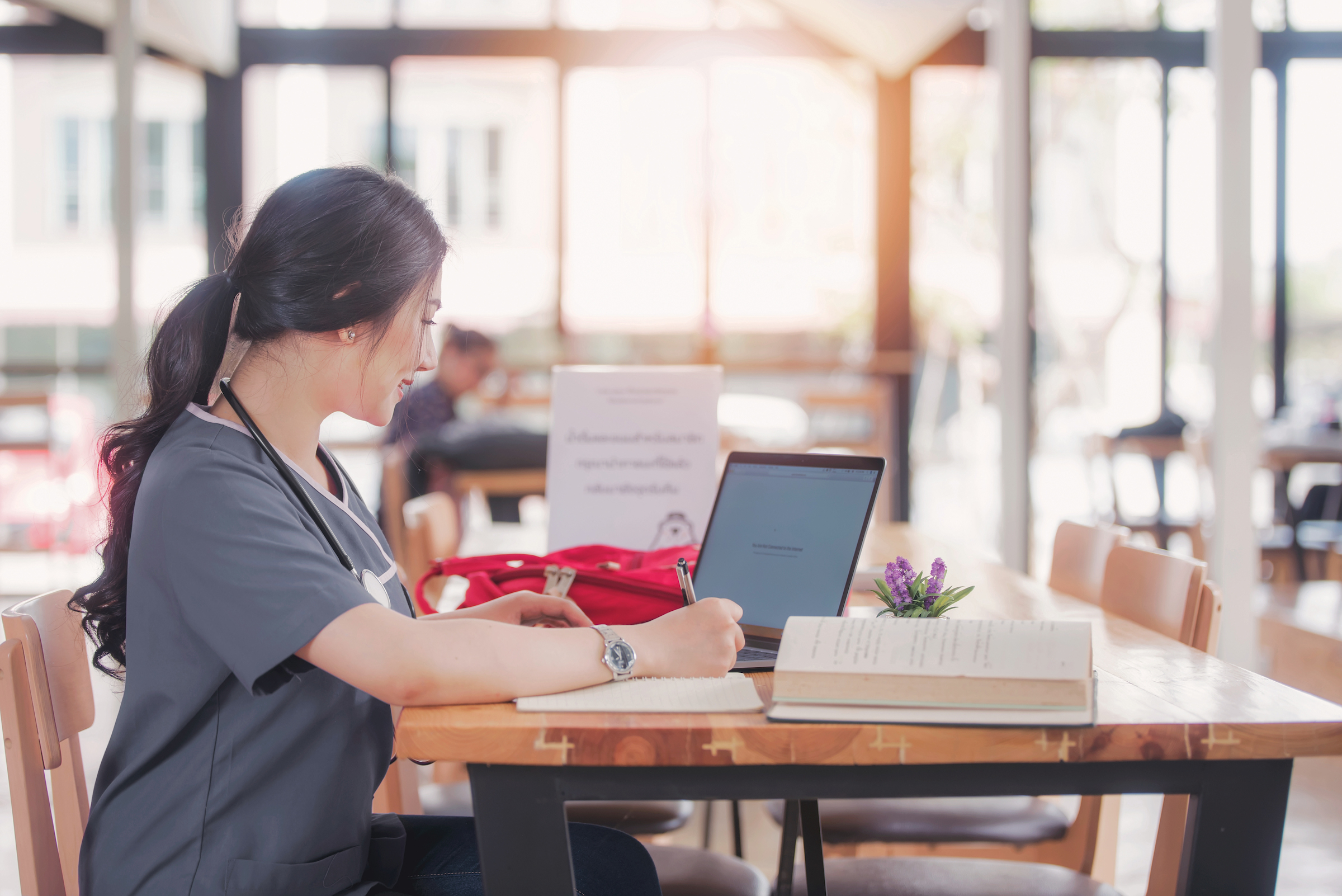 A medical professional studying in an open room with a laptop.