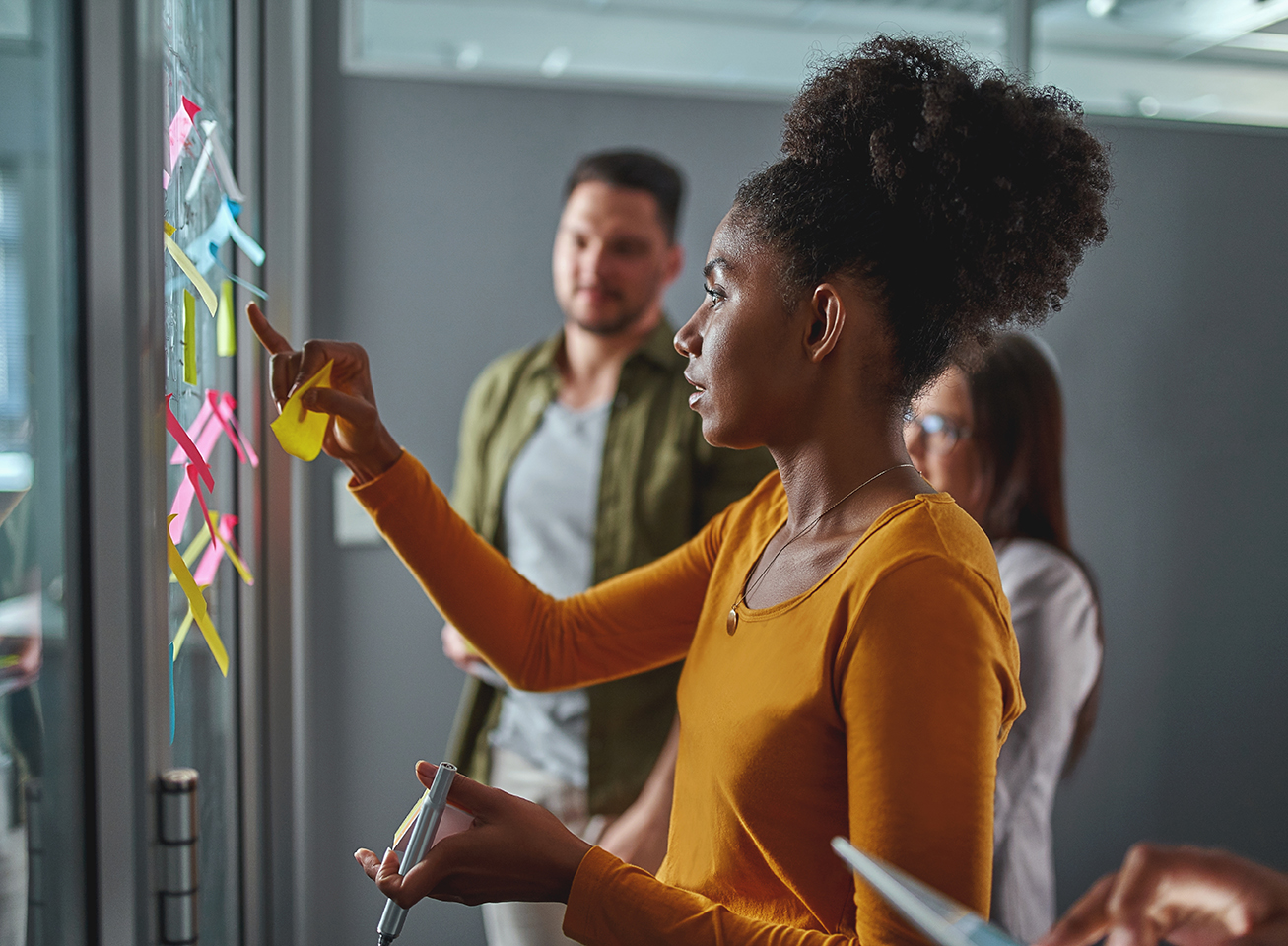 Woman adding post-it notes to board.