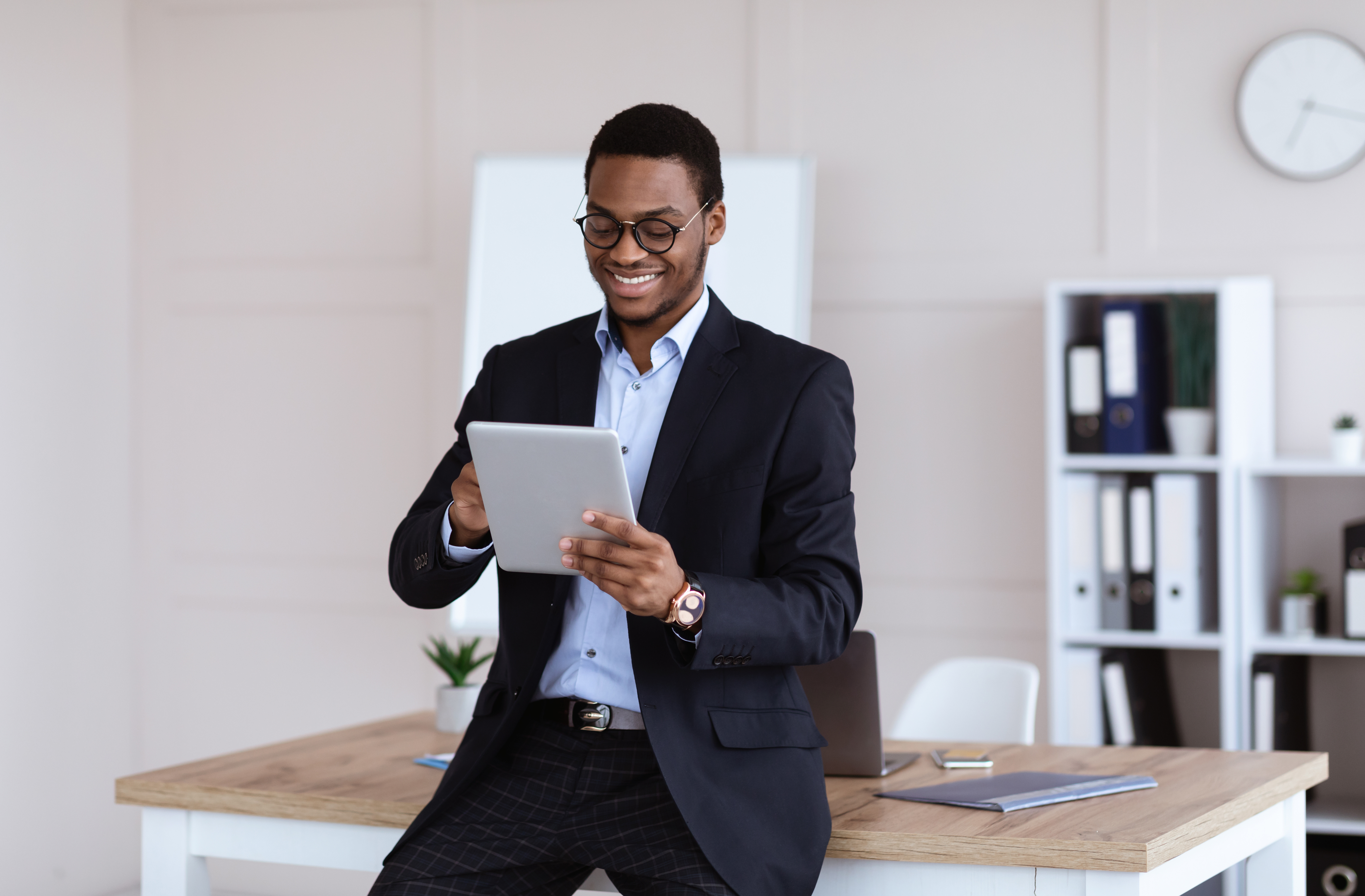 Man leaning against a desk and smiling while looking at a report.