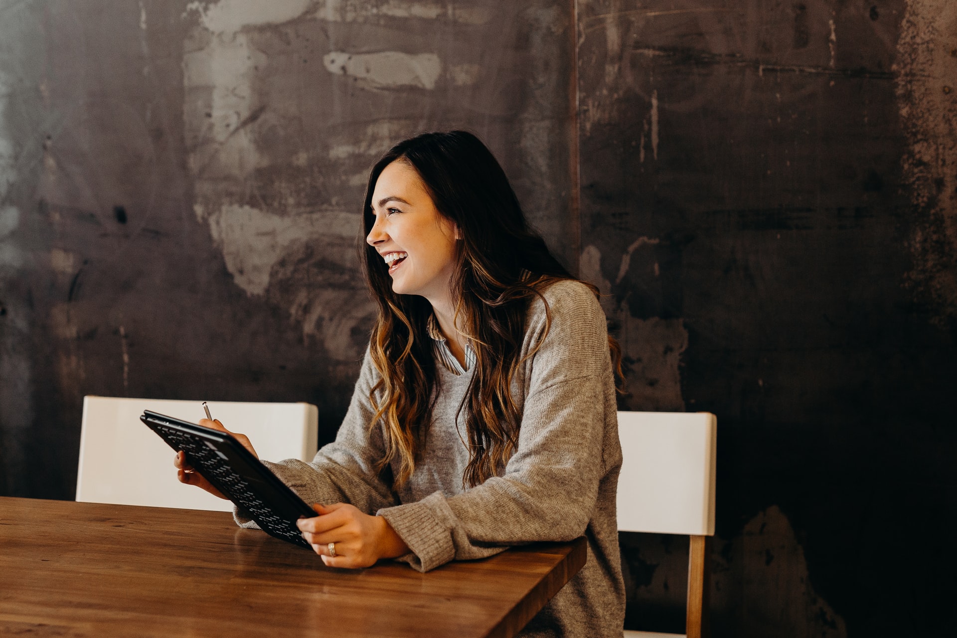 A woman sitting around a table holding a tablet.