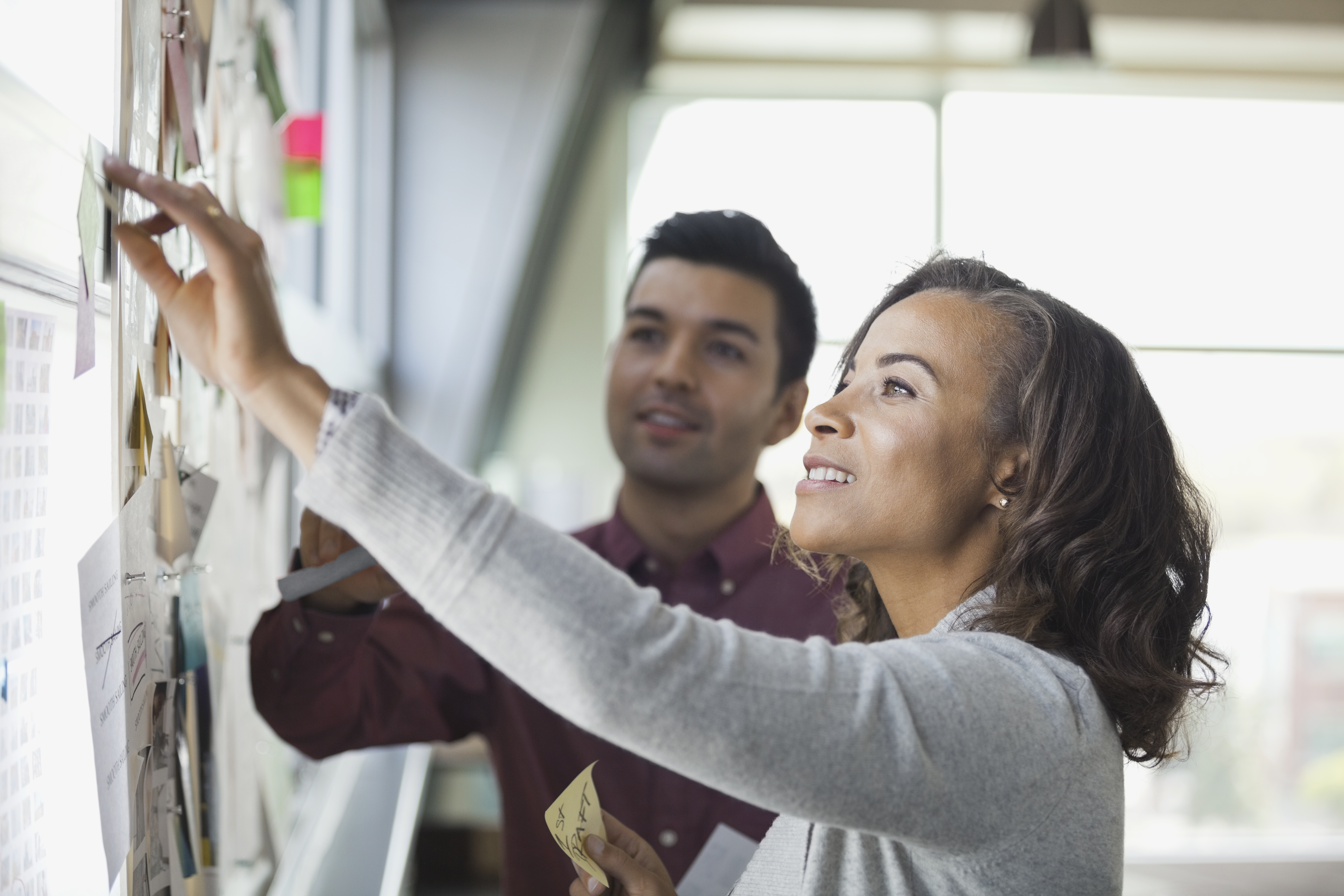 Two people looking at a board with notes.