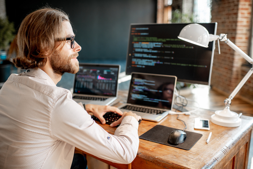 A man sitting at his desk looking at coding.