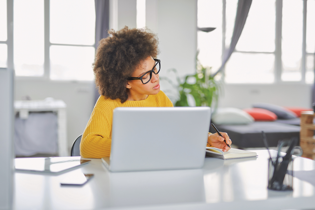 Businesswoman taking notes while sitting in office.