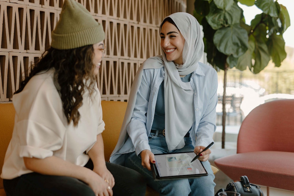 Two students talking to each other on a bench.