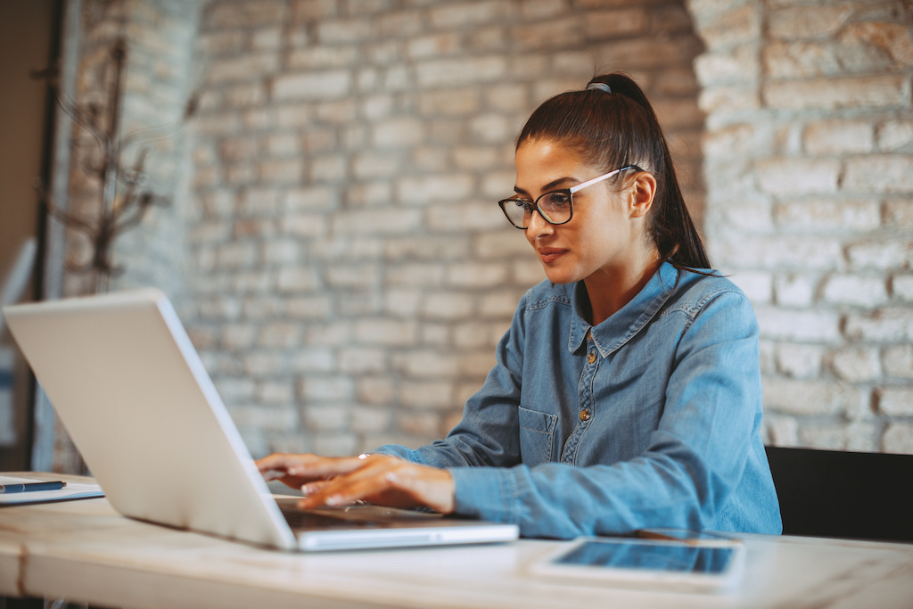 A student typing on her laptop at her desk.