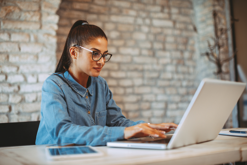 A student typing on her laptop at her desk.