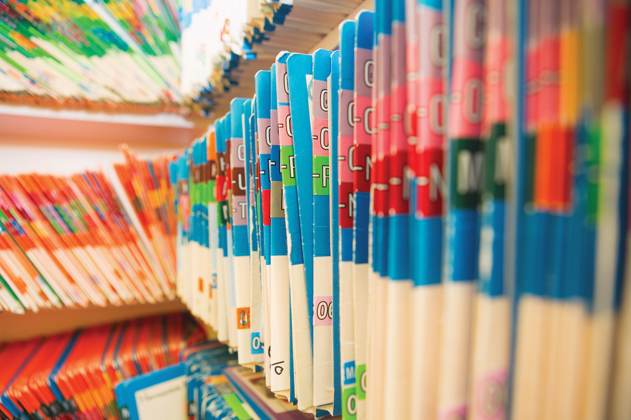 A row of medical files sit on a shelf.