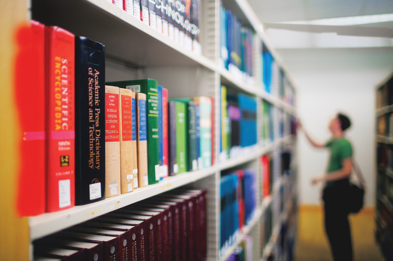 A person searching for medical writing books at a library.