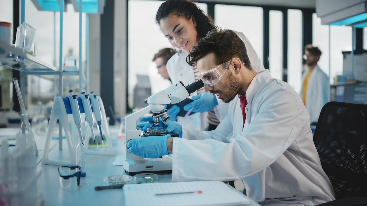 Clinical researchers conducting testing through a microscope.