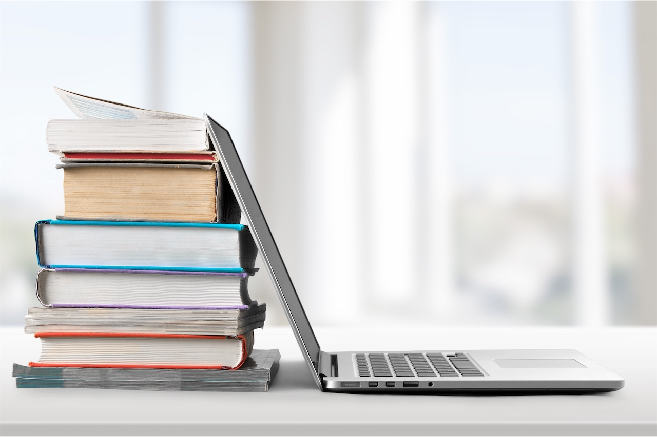 A laptop against a stack of books.