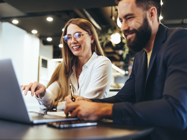 Cheerful businesspeople using a laptop in an office.