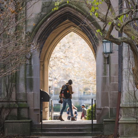 Student walking through archway on UChicago campus