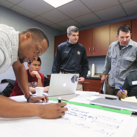 A group of people in a meeting room planning for a disaster drill.