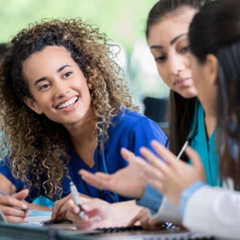 Medical students talking to each other in a classroom.