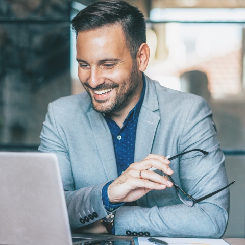 A man smiling and looking at his laptop.
