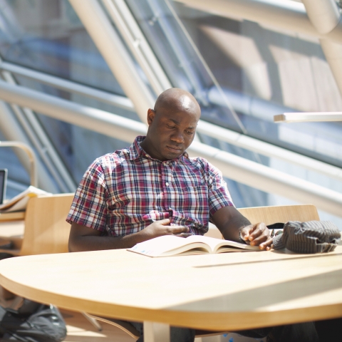 A Man sitting down reading a book at the UChicago campus.