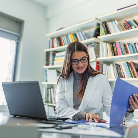 A medical professional reviews her notes in her office.
