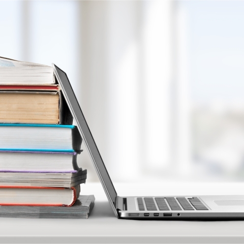 A laptop against a stack of books.