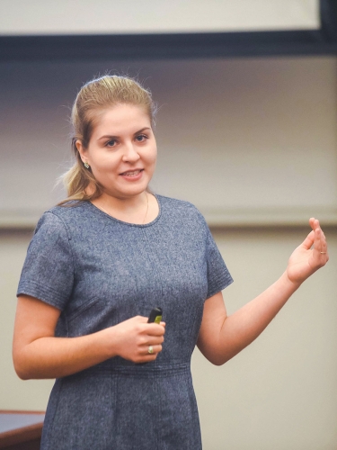 Person gesturing while standing in front of a class.
