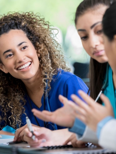 Medical students talking to each other in a classroom.