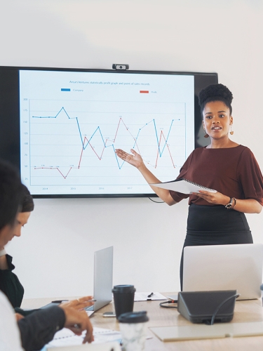 Woman standing in front of a presentation, gesturing to the screen.
