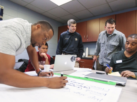 A group of people in a meeting room planning for a disaster drill.