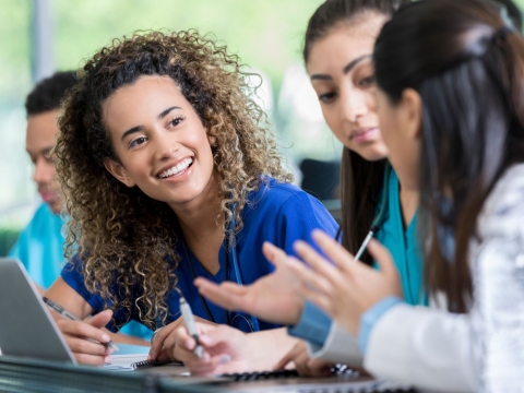 Medical students talking to each other in a classroom.