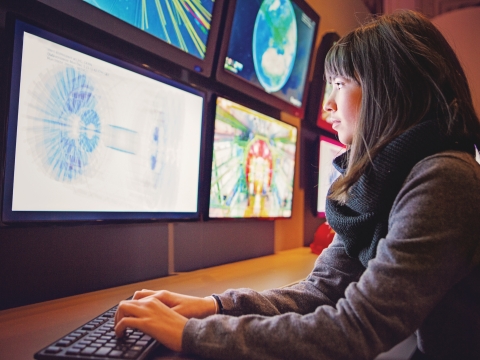 Woman looking into multiple monitor screens.