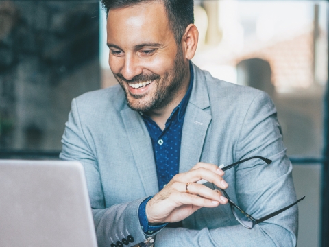 A man smiling and looking at his laptop.