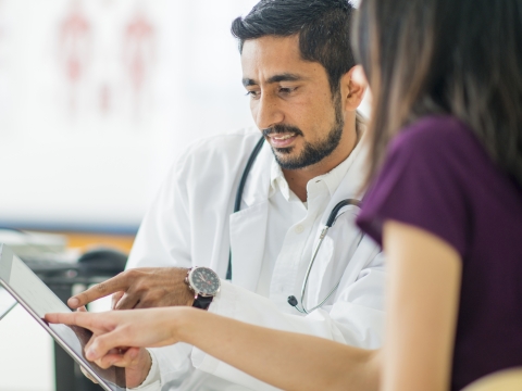 A doctor and nurse analyze a tablet.