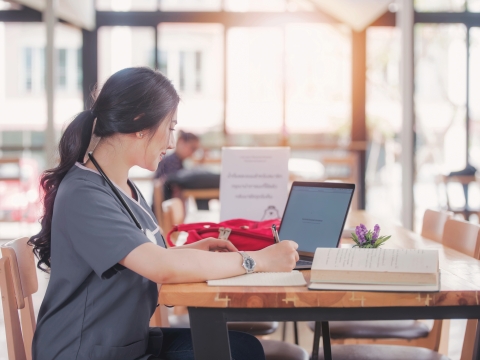 A medical professional studying in an open room with a laptop.