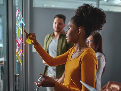 Woman adding post-it notes to board.