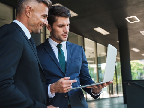 Business professionals reviewing content on a laptop.