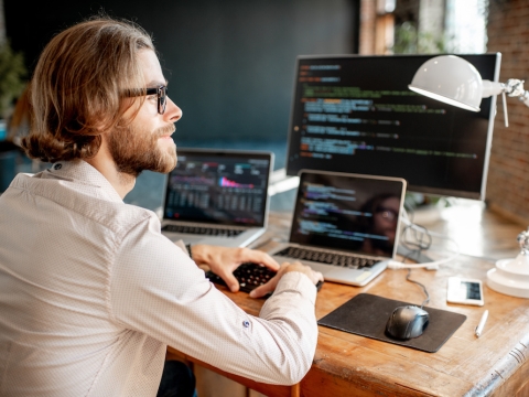 A man sitting at his desk looking at coding.