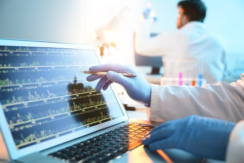 A lab tech studies medical information on a laptop.