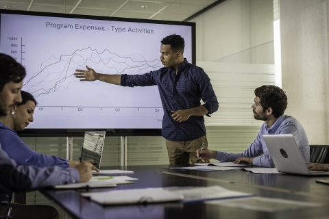 A student presents a graph in a conference room